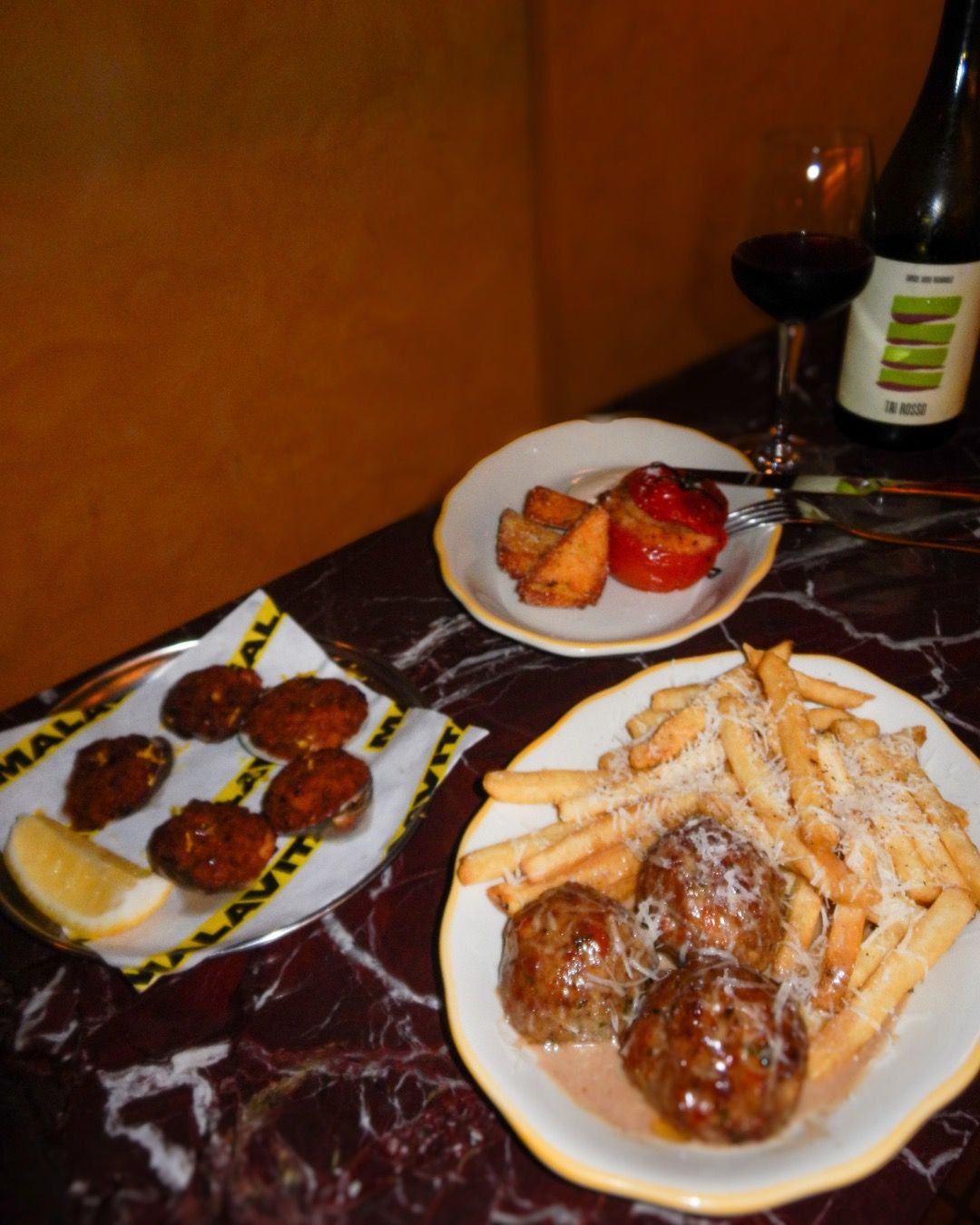 Baked clams, stuffed tomato, and meatballs with fries on the marble bar